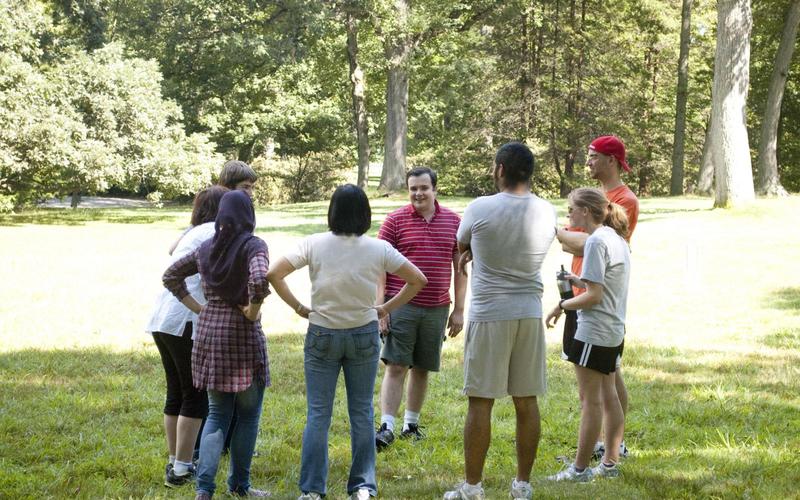 Group of people standing in a circle outside talking