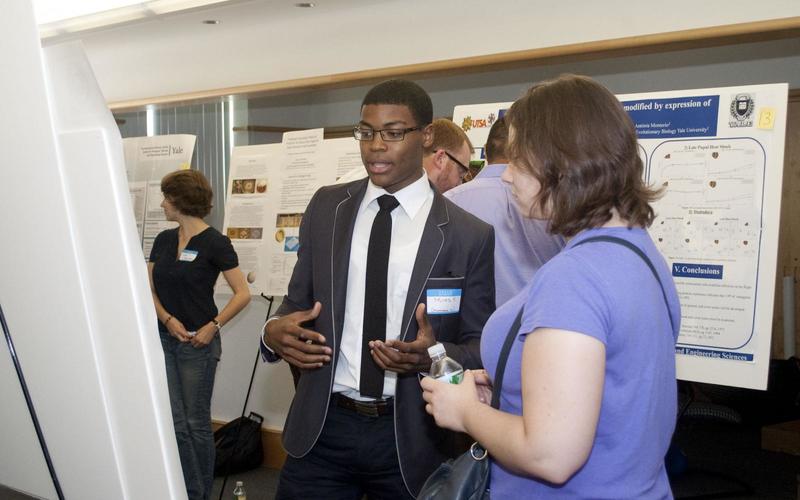 Undergraduate student talking to a visitor in front of his poster