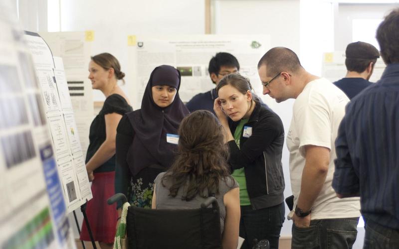 Undergraduate student talking to a group of visitors in front of her poster