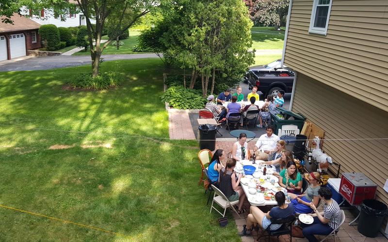 Two groups of people sitting around large tables in a backyard