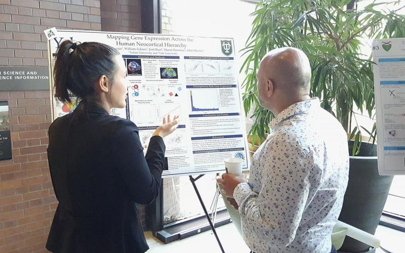 Undergraduate student talking to a visitor in front of her poster