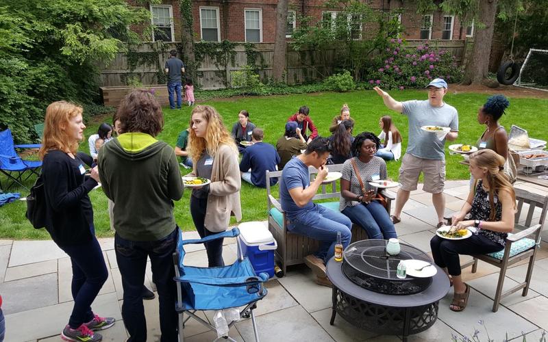 Several groups of people talking casually in a backyard