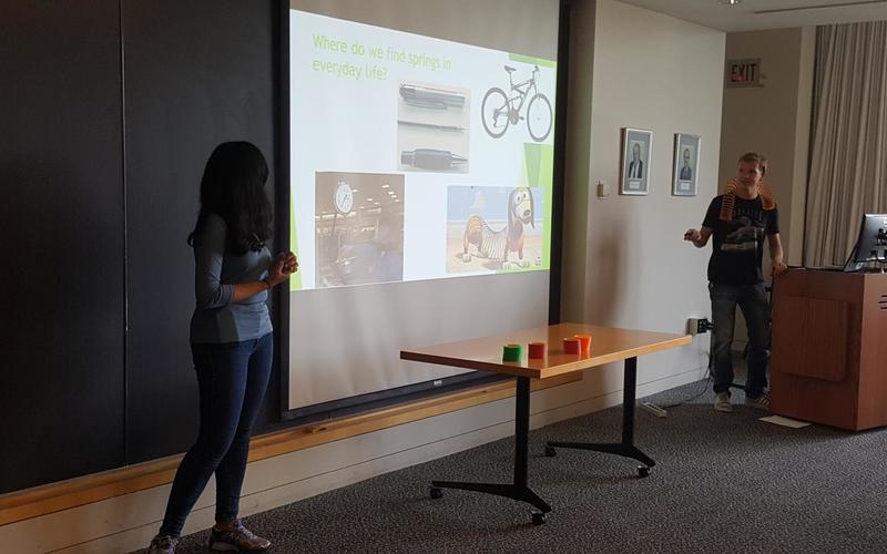 Two students standing in front of their powerpoint presentation 