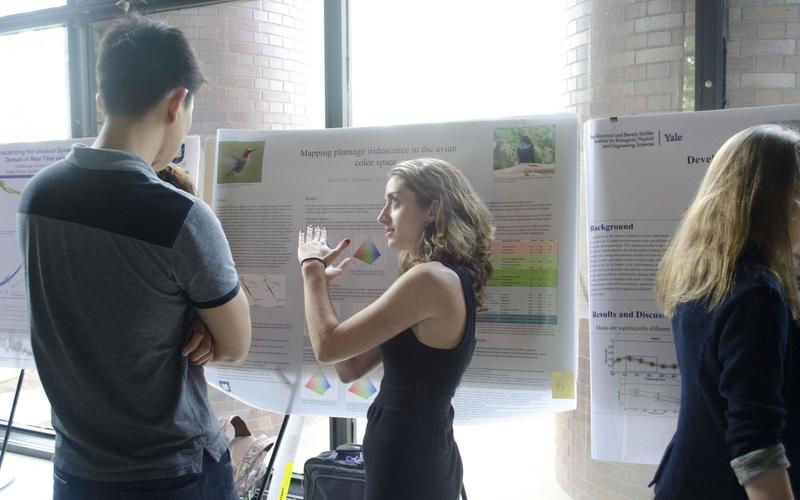 Undergraduate student talking to a visitor in front of her poster