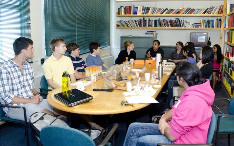 Students sitting around a large table talking with one another during a group activity