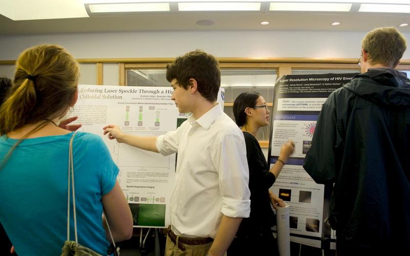 Undergraduate student talking to a visitor in front of his poster