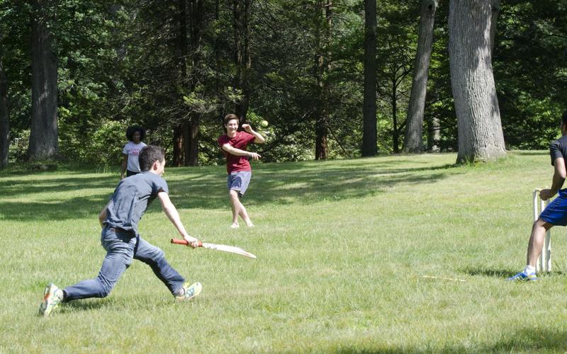 Students running toward one another during a cricket match