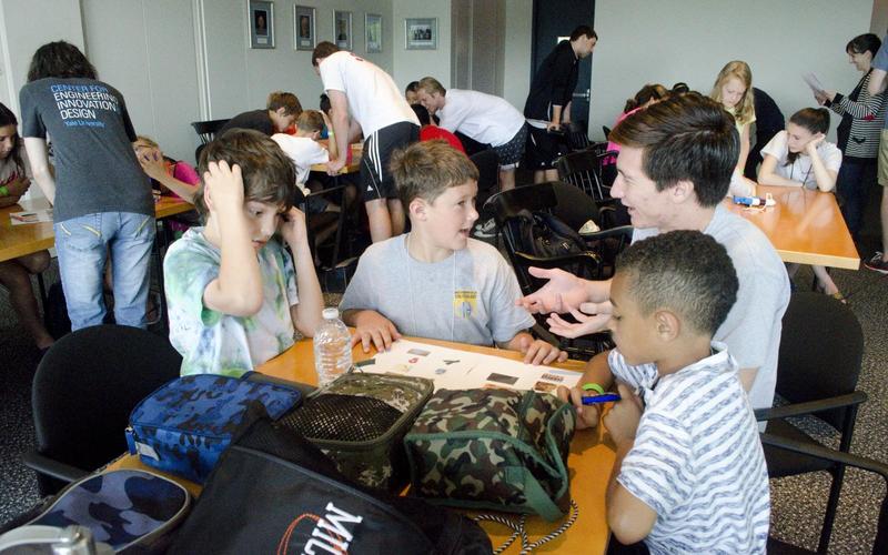 REU student talks to a group of 3 kids