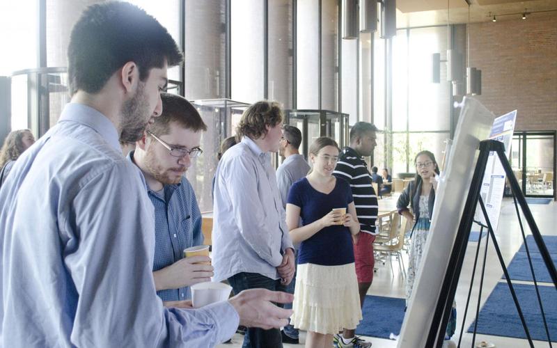 Undergraduate student talking to a visitor in front of his poster