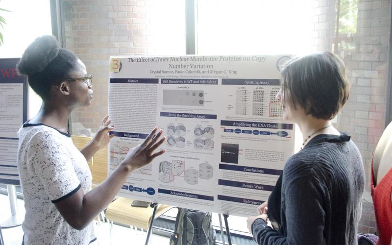 Undergraduate student talking to a visitor in front of her poster