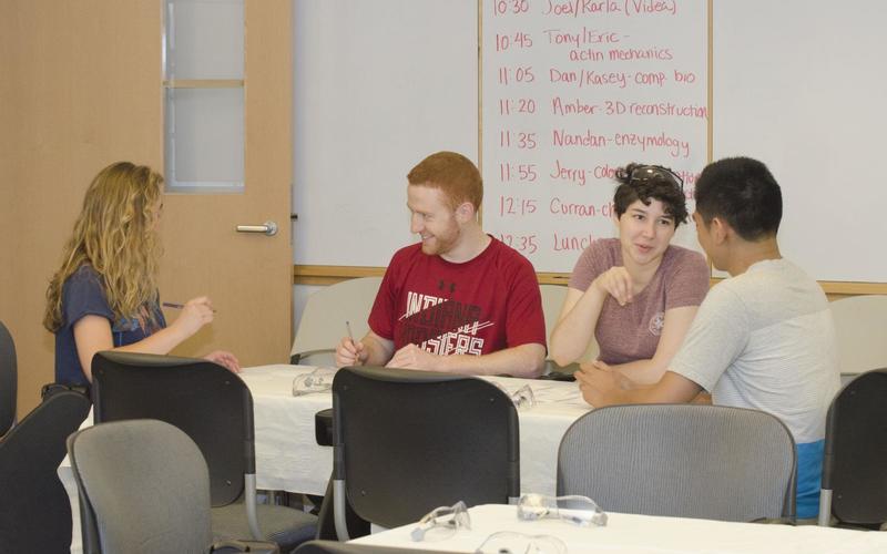 Students sitting around a large table talking with one another during a group activity