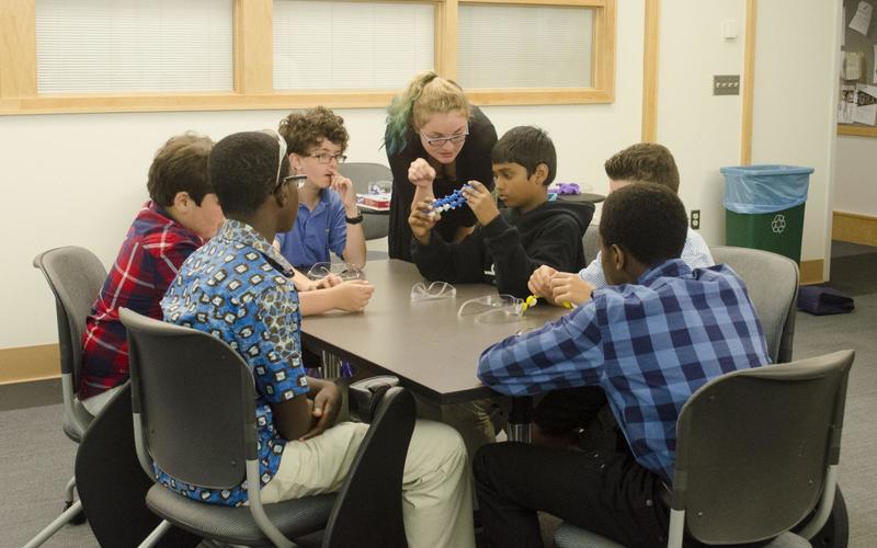 REU student talks to a small group of kids doing an activity