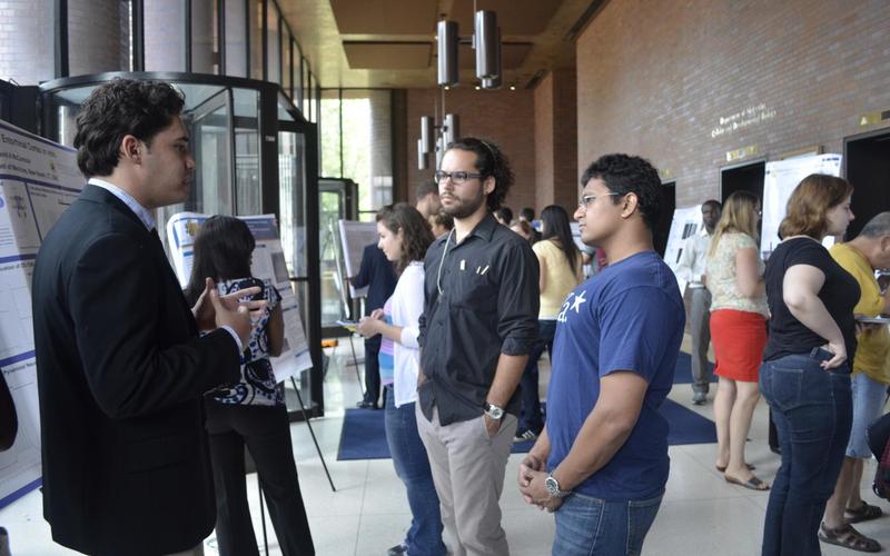 Undergraduate student talking to visitors in front of his poster