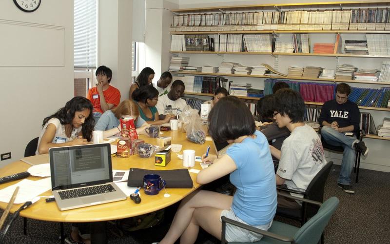 Students sitting around a large table talking with one another during a group activity