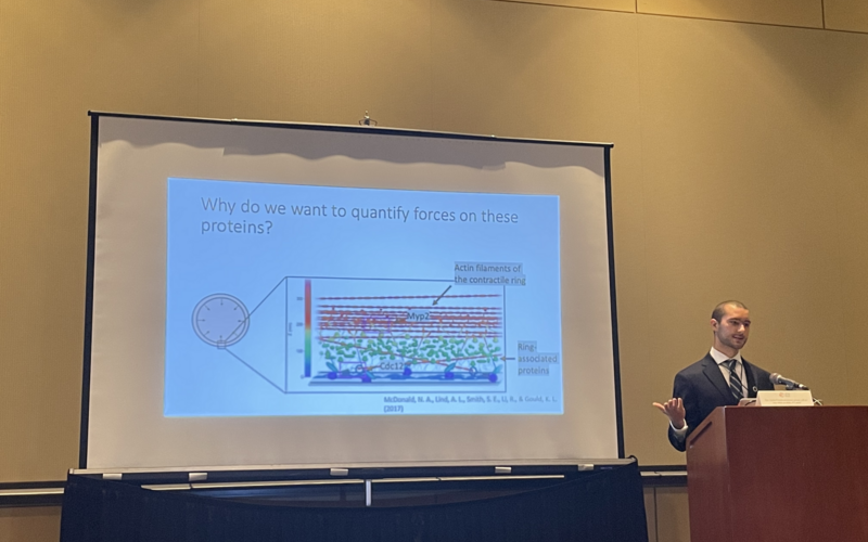 REU student standing in front of his slides while giving a talk