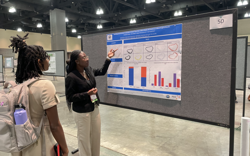 Undergraduate researcher presents her poster to a visitor