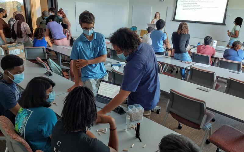 REU students talking to small groups of high school students during an outreach event