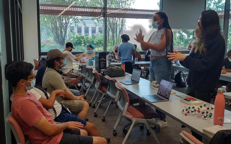 REU students talk to a small group of kids during an outreach activity