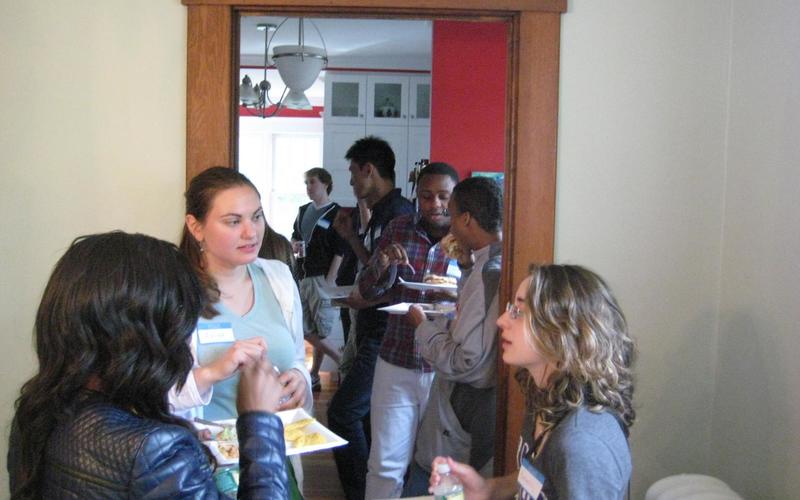 Small group people standing in a circle, talking, and eating snacks