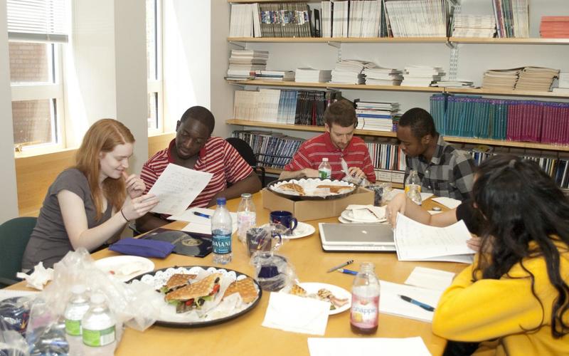 Students sitting around a large table talking with one another during a group activity