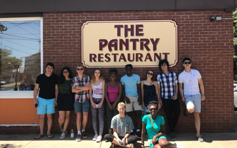 Group of REU students standing in front of the sign for the Pantry