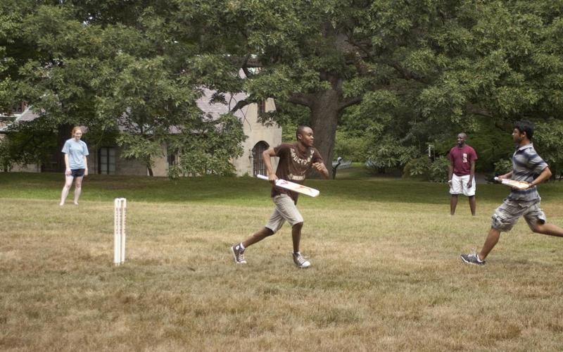 Two students run toward each other while playing cricket