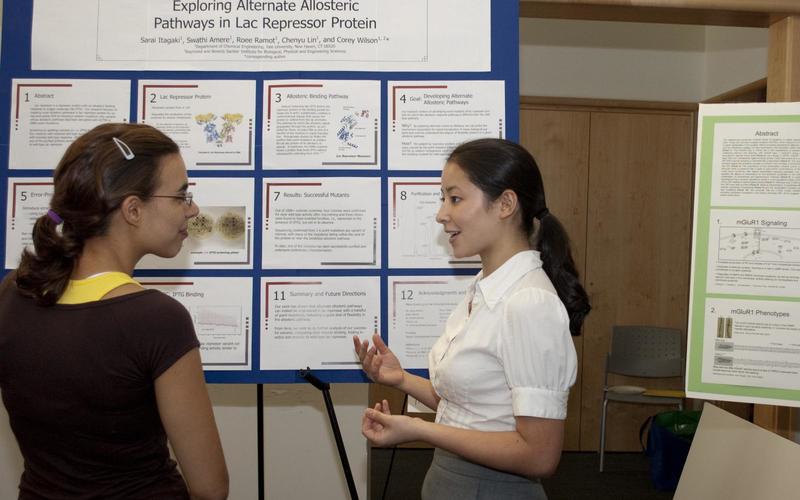 Undergraduate student talking to a visitor in front of her poster