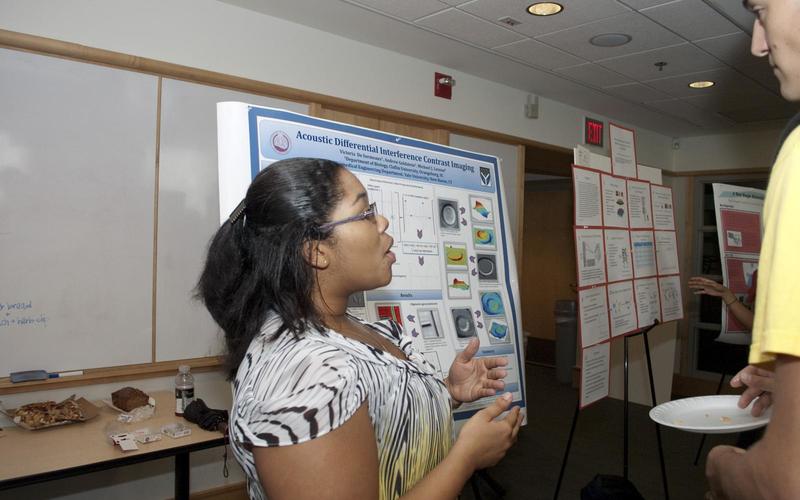 Undergraduate student talking to a visitor in front of her poster