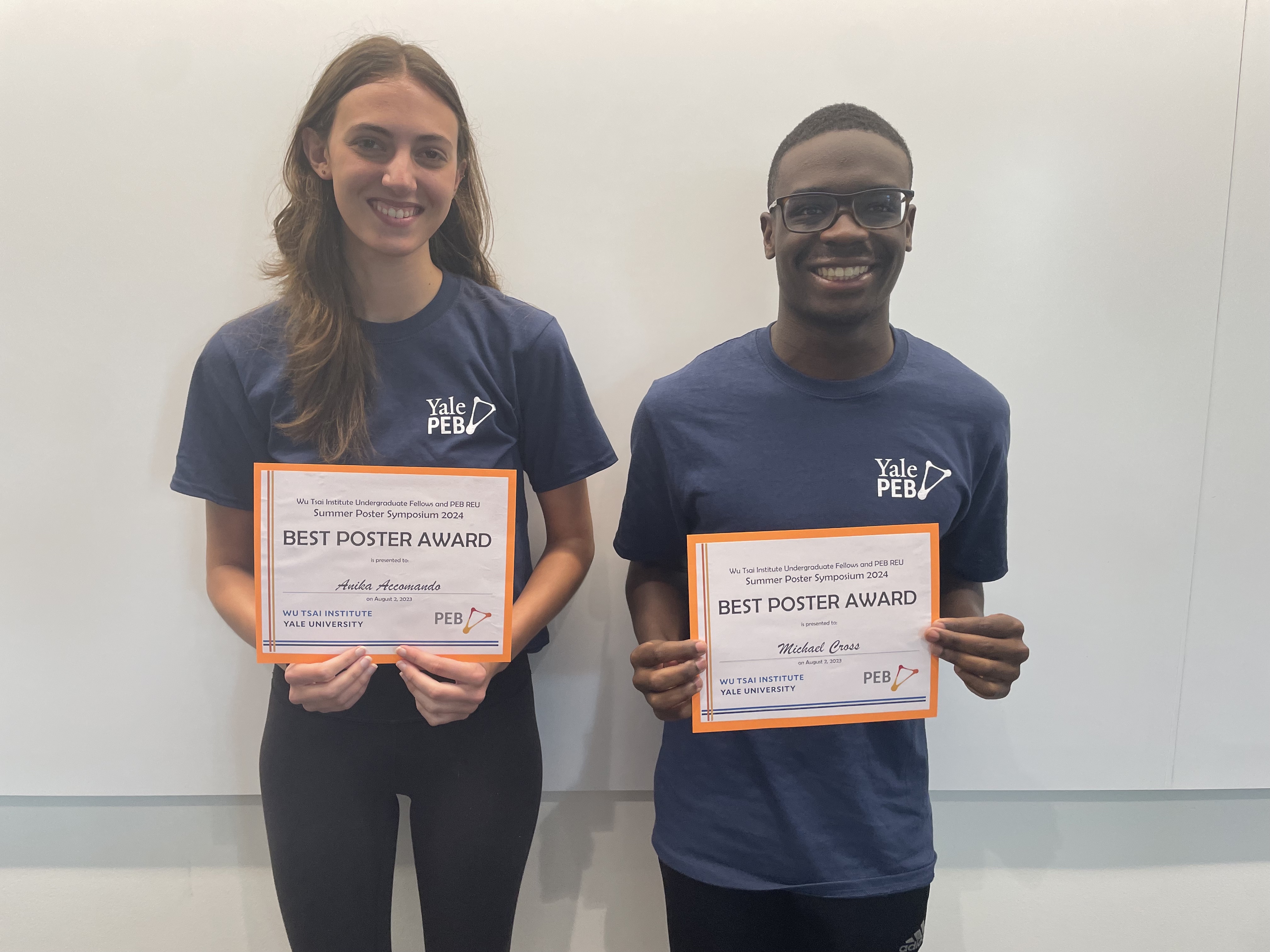 Anika and Michael holding their poster award certificates