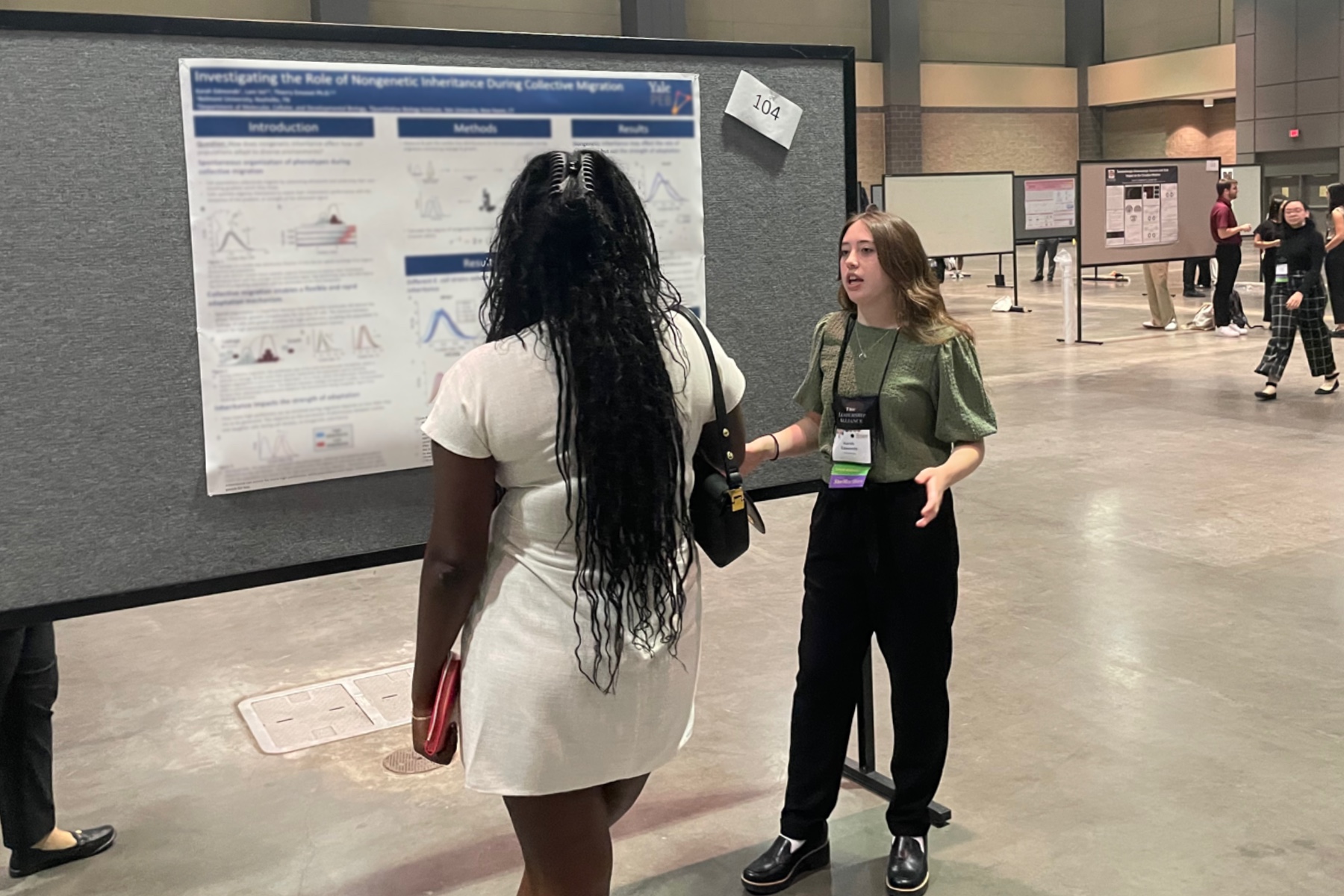 Karah standing in front of her research poster at LANS talking with a visitor