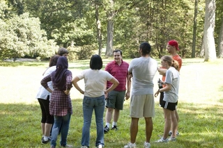 Group of people standing in a circle outside talking