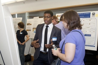 Undergraduate student talking to a visitor in front of his poster