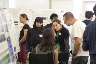 Undergraduate student talking to a group of visitors in front of her poster