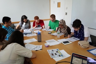 Students sitting around a large table reading a paper during a group activity