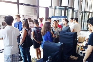 Large group of people talking with one another with posters around the perimeter of the room