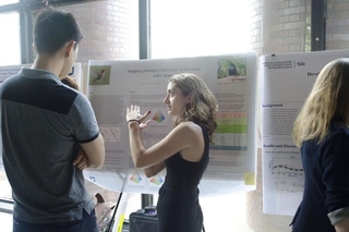 Undergraduate student talking to a visitor in front of her poster