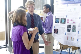 Undergraduate student talking to a visitor in front of his poster