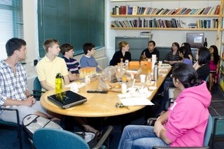 Students sitting around a large table talking with one another during a group activity