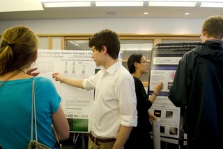 Undergraduate student talking to a visitor in front of his poster