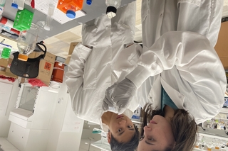Undergraduate researcher adds bacteria to a capillary tube with her graduate student mentor watching.