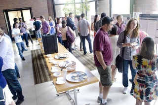 Large group of people talking with one another with posters around the perimeter of the room