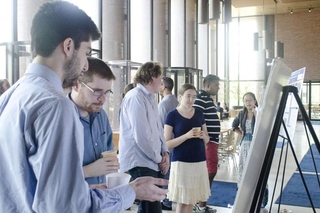 Undergraduate student talking to a visitor in front of his poster