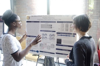 Undergraduate student talking to a visitor in front of her poster