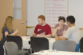 Students sitting around a large table talking with one another during a group activity