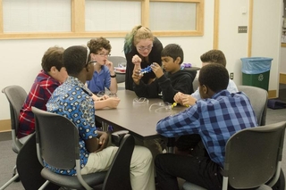 REU student talks to a small group of kids doing an activity