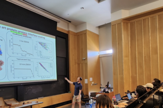 PEB student pointing at slide while presenting research