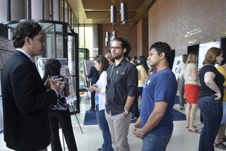 Undergraduate student talking to visitors in front of his poster