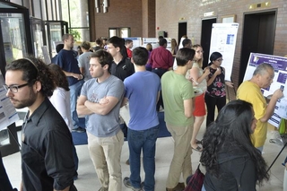 Large group of people talking with one another with posters around the perimeter of the room