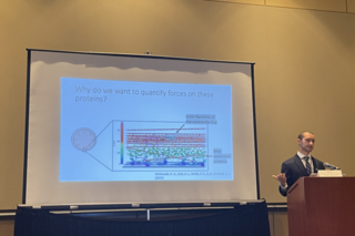 REU student standing in front of his slides while giving a talk