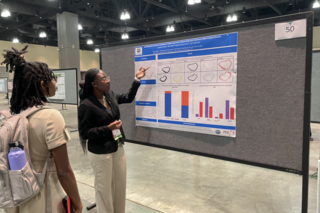 Undergraduate researcher presents her poster to a visitor